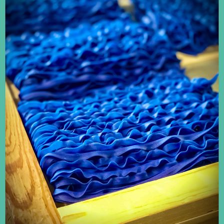 Ein Nahaufnahme eines Holzkastens, gefüllt mit blauen Rüschenbändern, ordentlich gestapelt und organisiert.