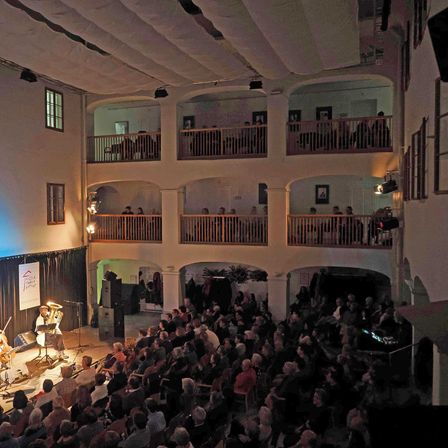 Bild enthält, People, Person, Auditorium, Indoors, Theater, Crowd, Building, Urban, Classroom, Painting