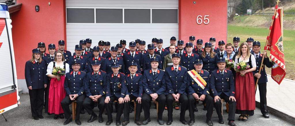 Eine Gruppe Feuerwehrleute in Uniform posiert für ein Foto vor einer Feuerwache.
