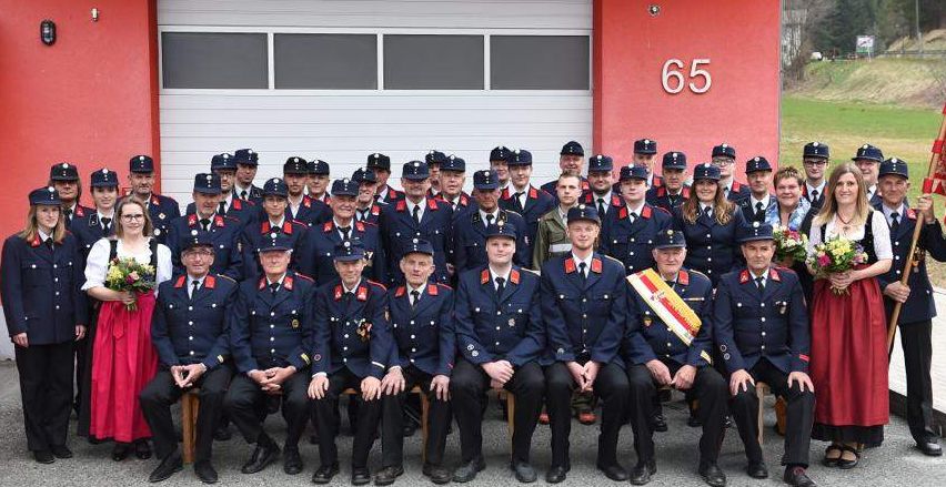 Eine Gruppe Feuerwehrleute in Uniform posiert für ein Foto vor einer Feuerwache.