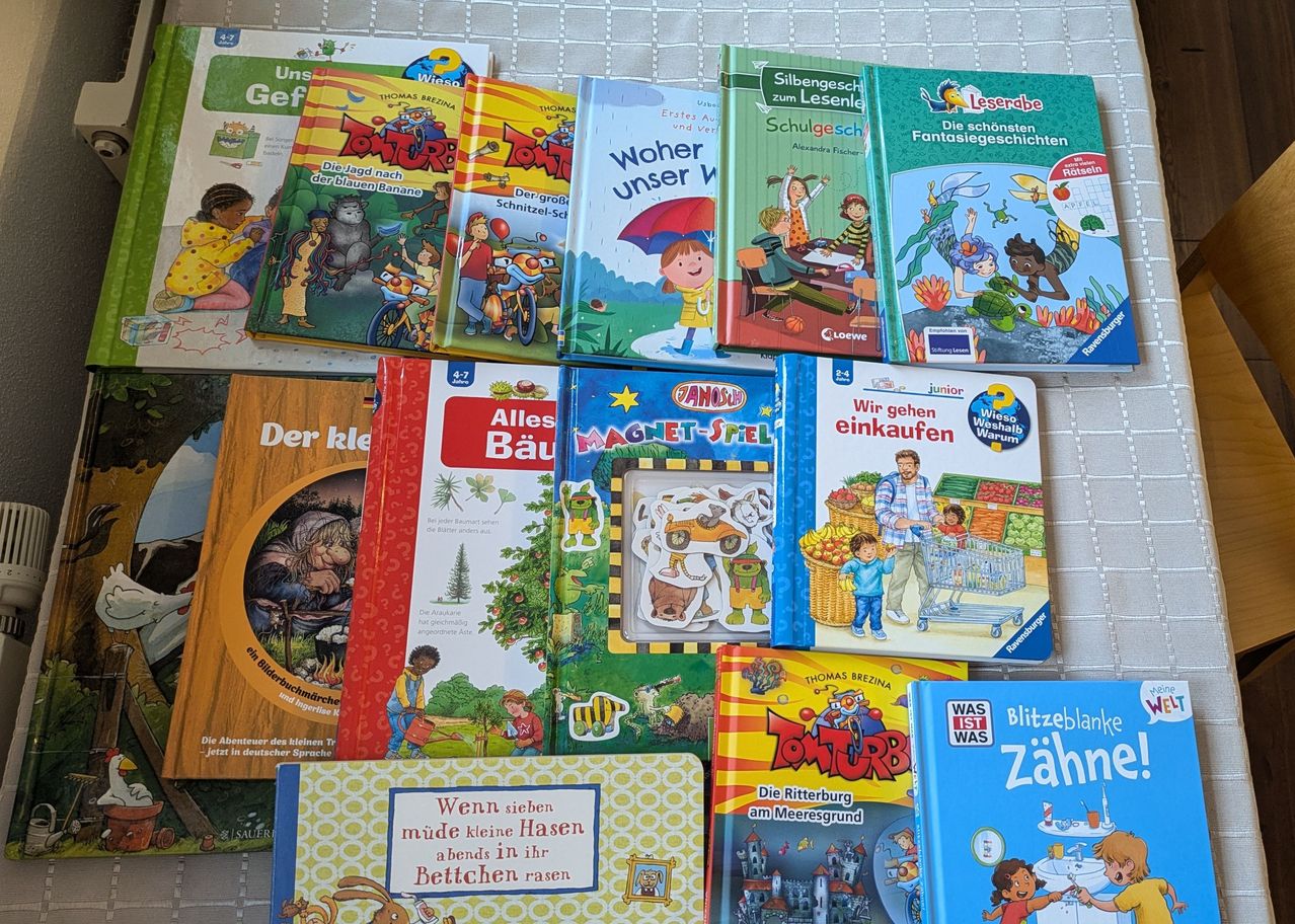 Eine Sammlung von Kinderbüchern, die auf einem Tisch ausgestellt sind, einschließlich Titel wie 'TomTurbo', 'Was Ist Was' und 'Blitzeblank Zahn'. Die Bücher haben farbenfrohe Illustrationen und fesselnde Geschichten.