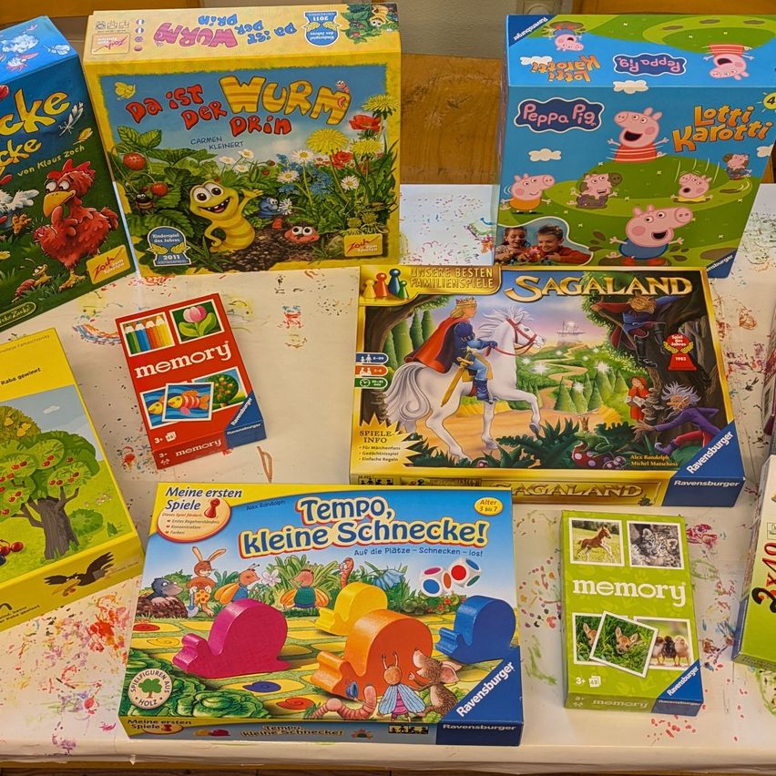 Ein Tisch zeigt verschiedene Brettspiele, darunter Peppa Pig, Sagaland, Da ist Wurm der Priin, Meine ersten Spiele und Tempo kleine Schnecken! Bunte und thematische Schachteln mit verschiedenen Charakteren.