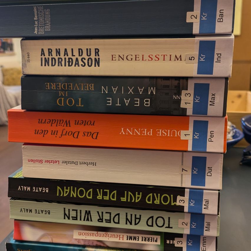A stack of books in different colors and sizes with labels such as 'Engelsstämm', 'Barn', 'Max', 'Pen', 'Dut', 'Mal', 'Emm', and prices like 2 Kr, 5 Kr, 3 Kr, 1 Kr, 7 Kr, 3 Kr, 2 Kr, 3 Kr.
