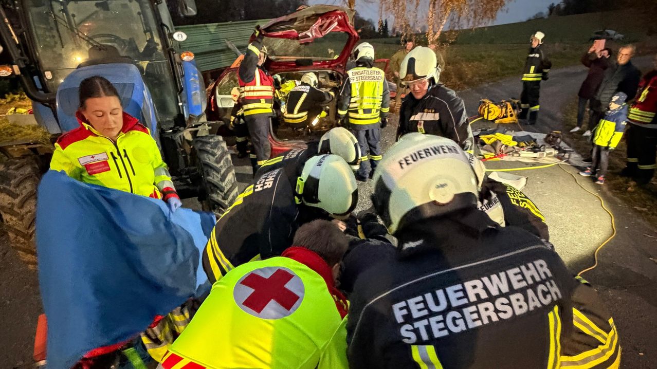 Rettungskräfte kümmern sich um verletzte Personen an einem Unfallort, mit Rettungsfahrzeugen und Ausrüstung in der Nähe.