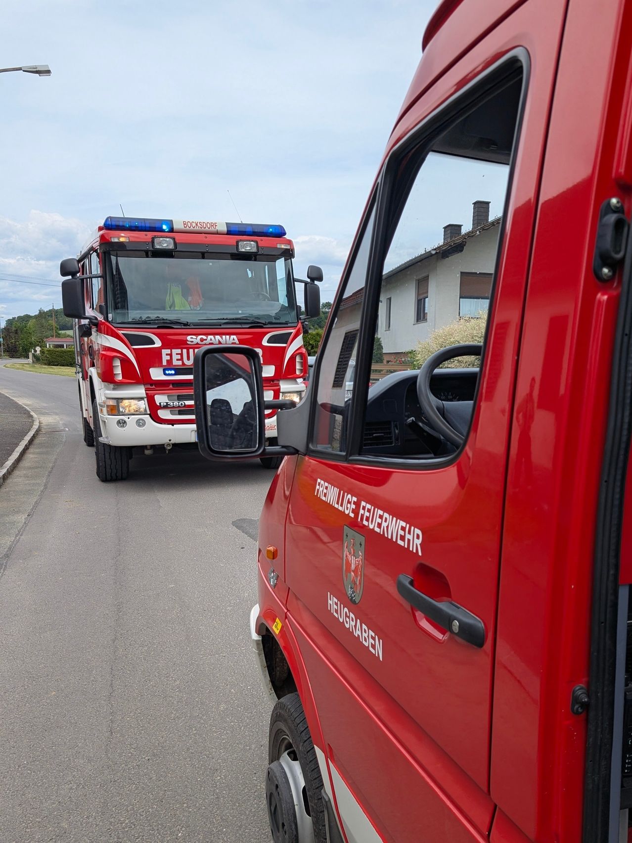 Zwei rote Feuerwehrfahrzeuge sind auf der Straße geparkt. Ein Gebäude steht hinter den Fahrzeugen. Das Wort Feu steht auf der Vorderseite des Fahrzeugs.