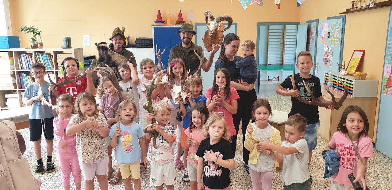 A group of children and adults are posing for a photo in a room with animal skulls and antlers on display.