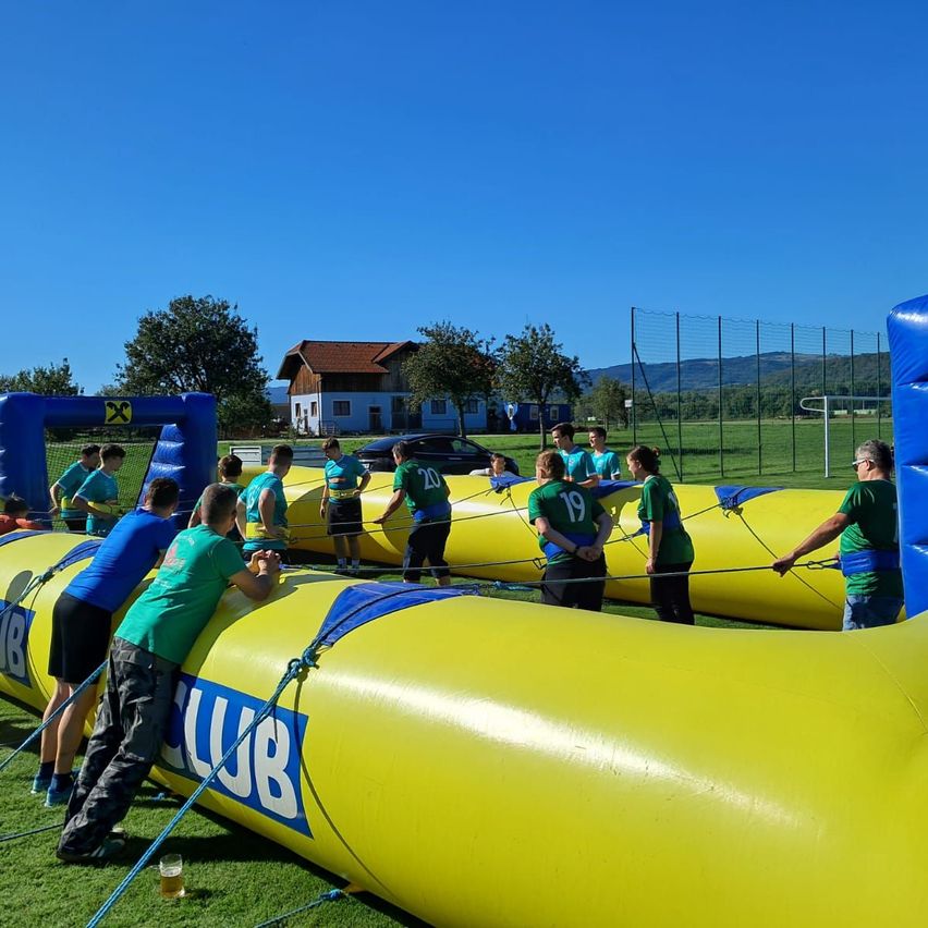 Eine Gruppe von Menschen spielt ein Spiel auf einem Feld mit aufblasbaren Hindernissen.