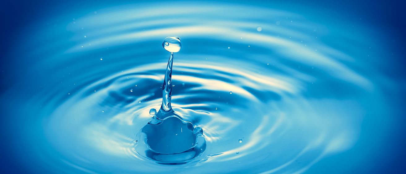 Ein Wassertropfen spritzt in einen blauen Pool und erzeugt dabei Wellen und winzige Tröpfchen um ihn herum.