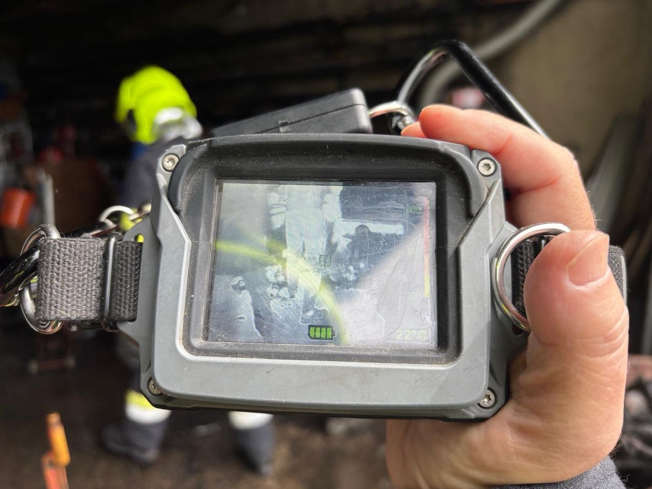 Eine Hand hält eine robuste Kamera, die ein verschwommenes Bild einer Person in einem Tunnel anzeigt.