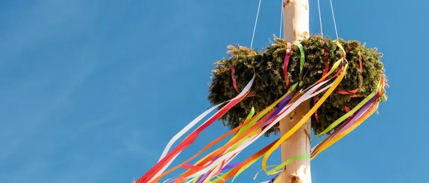 Eine bunte Bandschleife hängt an einem Pfosten am blauen Himmel, möglicherweise für ein Festival.