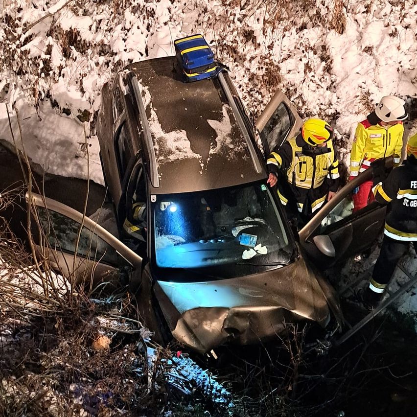 Rettungskräfte in reflektierenden Westen helfen den Insassen aus einem verunglückten SUV auf einer verschneiten Straße.