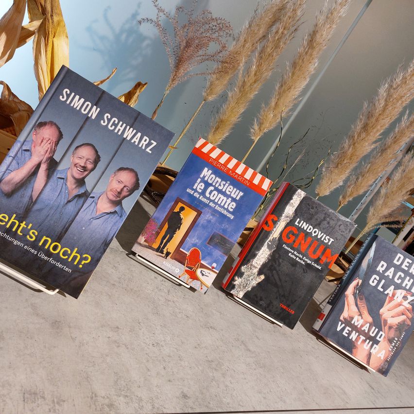 Vier Bücher sind auf einem Tisch angeordnet. Das erste Buch trägt den Titel 'Ist es noch nicht vorbei?' von Simon Schwarz. Das zweite Buch trägt den Titel 'Monsieur de Comte' von Pierre Martin. Das dritte Buch trägt den Titel 'Gnum' von Lindqvist. Das vierte Buch trägt den Titel 'Die schmutzige Hand' von Maud Ventura.