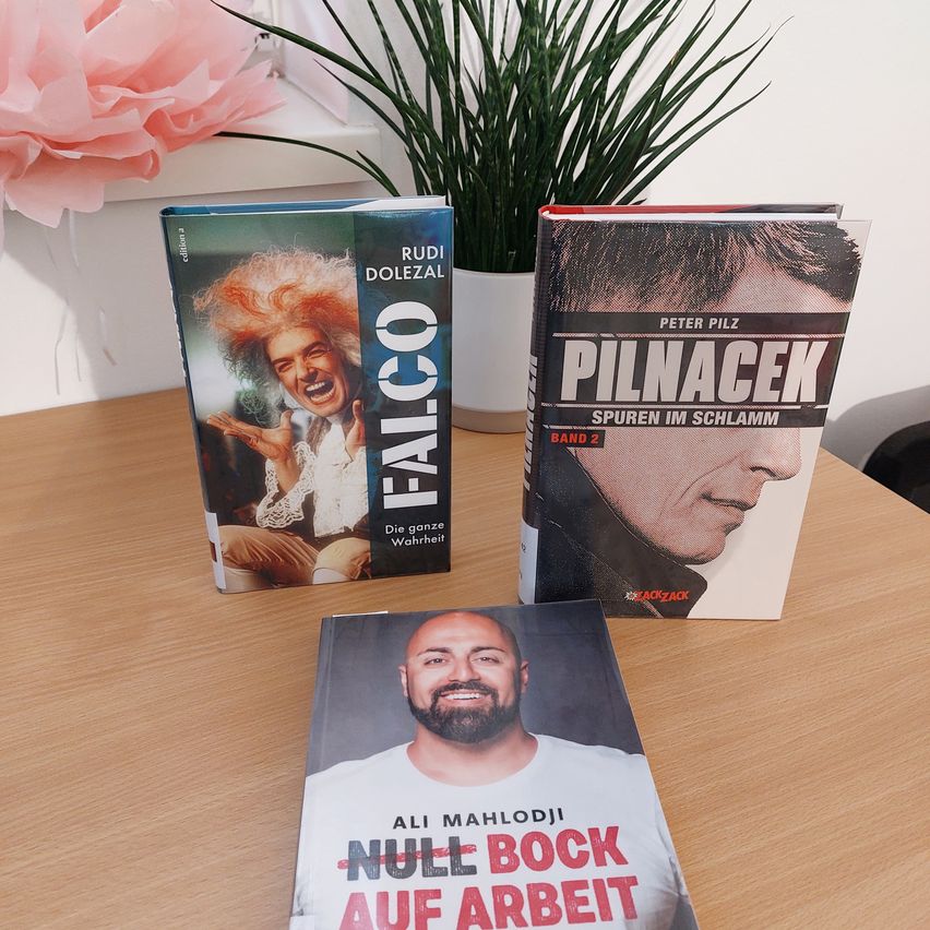 Three books on a table. 'FALCO' by Rudi Dolezal, 'Pilnaček Spuren Im Schlamm' by Peter Pilz, and 'Null Bock Auf Arbeit' by Ali Mahlodji.