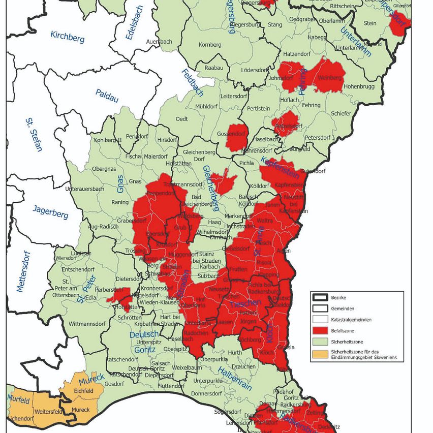Die Karte zeigt die Verwaltungsgliederung einer Region, mit verschiedenen Bezirken und Gemeinden beschriftet. Verschiedene Farben unterscheiden jedes Gebiet, einschließlich einer roten Region mit der Bezeichnung 'Sicherheitszone'. Die Karte enthält eine Legende mit farbkodierten Erklärungen zu jedem Gebiet.