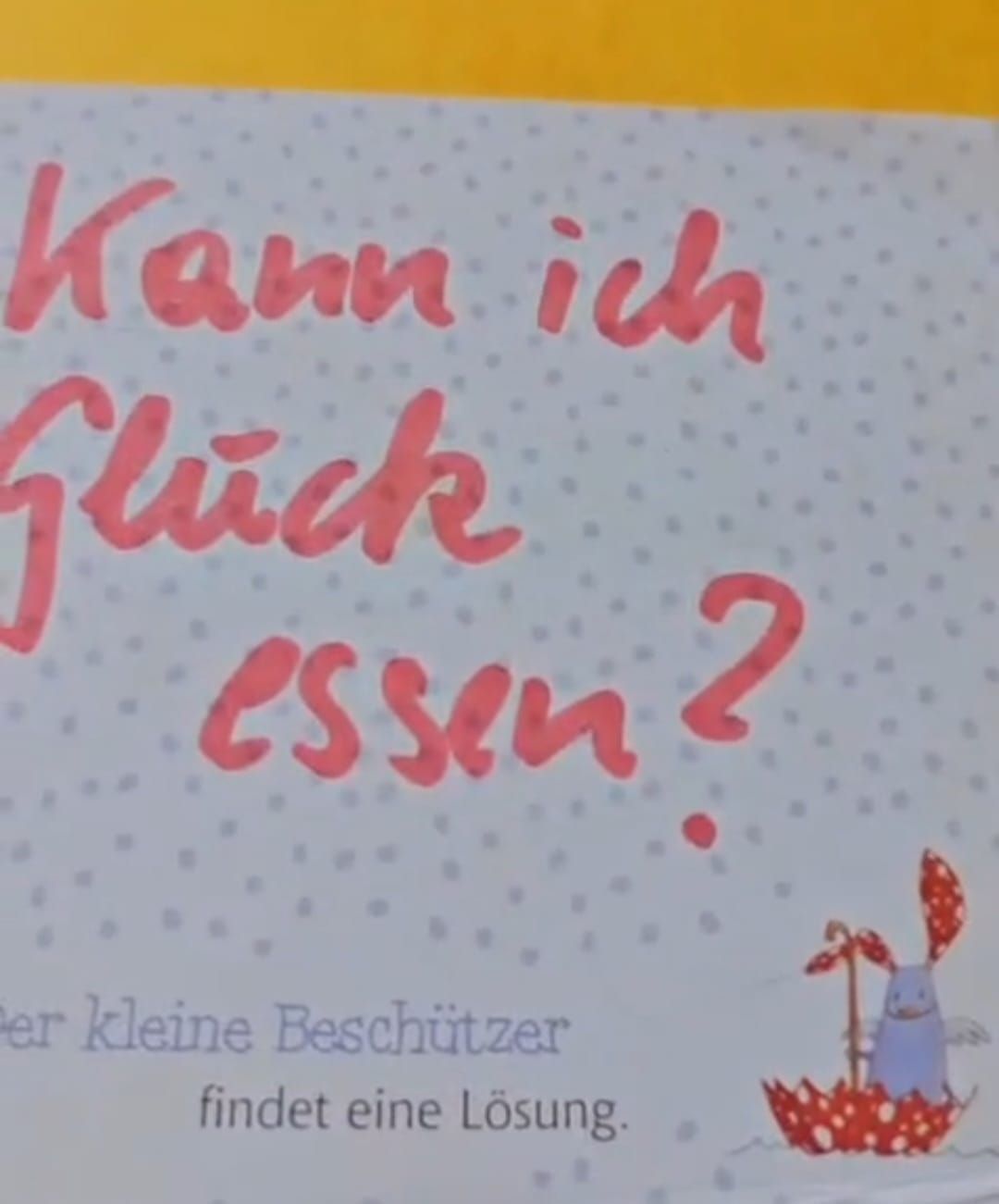 Eine weiße Seite mit rotem Text, der fragt 'Kann ich Glück essen?' und einer kleinen Illustration einer Figur mit einer Flagge.