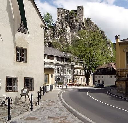 Eine Straße mit einem Kopfsteinpflaster, einem geparkten Fahrrad und Gebäuden, einschließlich einer Burg auf einem Hügel.
