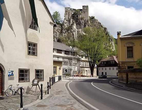 Eine Straße mit einem Kopfsteinpflaster, einem geparkten Fahrrad und Gebäuden, einschließlich einer Burg auf einem Hügel.