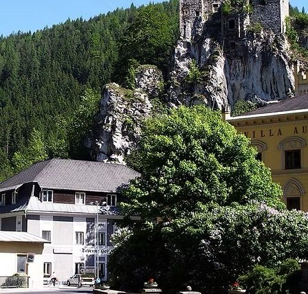 Eine Stadt mit Gebäuden, einer Burg und einem Berg. Die Burg steht auf dem Berg. Bäume und Pflanzen umgeben das Gebiet.