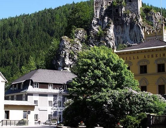 Eine Stadt mit Gebäuden, einer Burg und einem Berg. Die Burg steht auf dem Berg. Bäume und Pflanzen umgeben das Gebiet.
