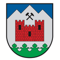 Ein Schild mit einer roten Burg und einem Hammer auf einem Berg, umgeben von einem grünen Rand.
