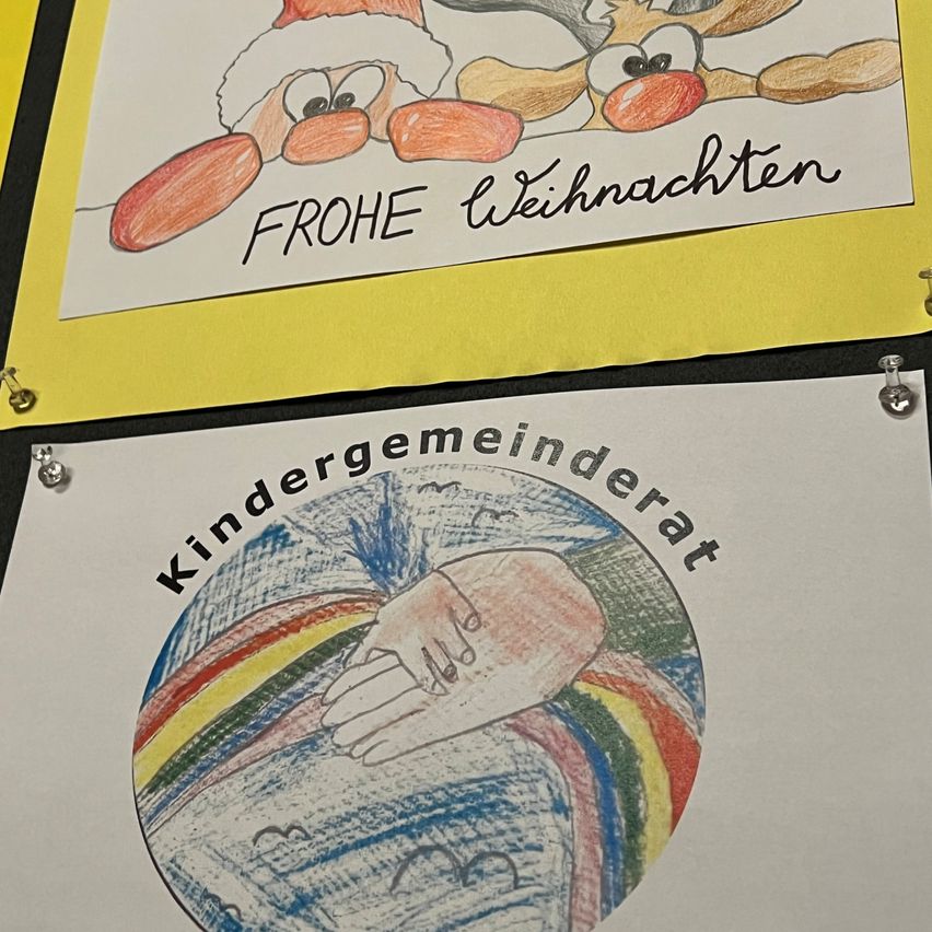 Zwei Zeichnungen auf Papier, eine mit zwei Rentieren und den Worten 'FROHE WEIHNACHTEN' und die andere mit einem Globus und den Worten 'Kindergemeinderat'.
