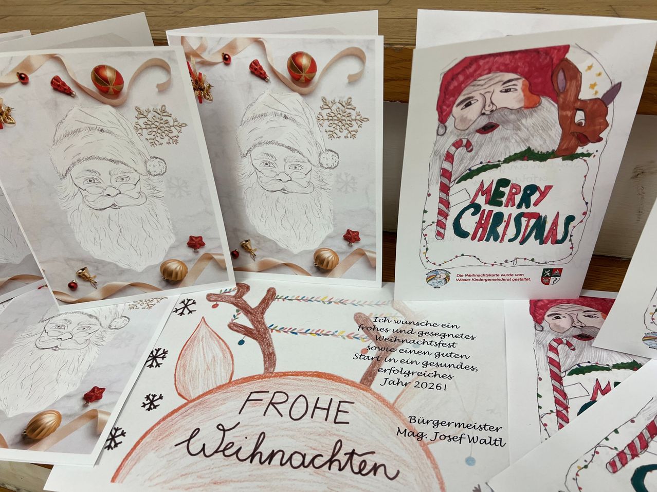 Eine Sammlung von Weihnachtskarten mit verschiedenen Illustrationen von Santa Claus und Winterelementen. Die Karten haben handgeschriebene Feiertagsgrüße auf Deutsch, einschließlich 'Frohe Weihnachten' und 'Merry Christmas'.