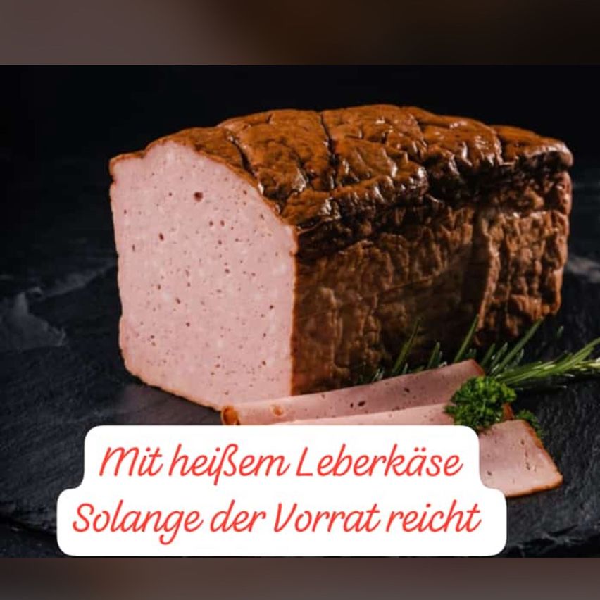 Ein geschnittenes Stück Leberkäse mit brauner Kruste, garniert mit Rosmarin, auf einer schwarzen Oberfläche mit einem weißen Textüberlagerung, der 'mit heißem Leberkäse Solange der Vorrat reicht' lautet.