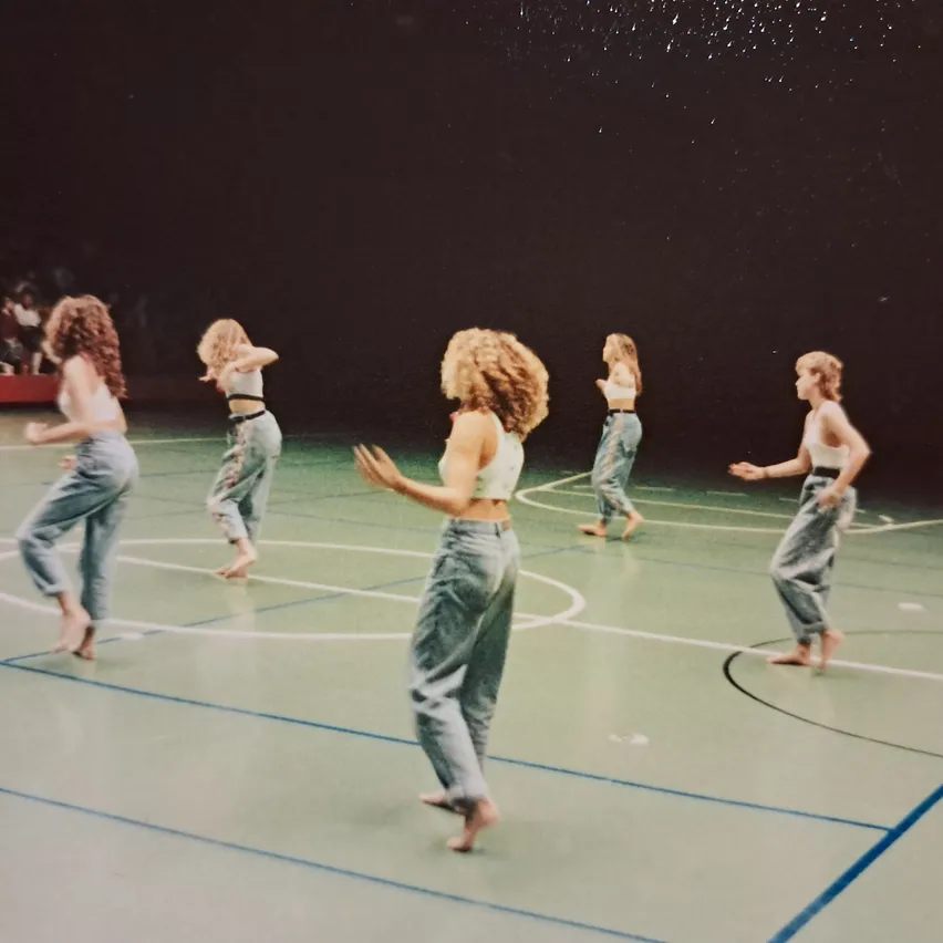 Eine Gruppe von Frauen tanzt auf einem Basketballplatz.