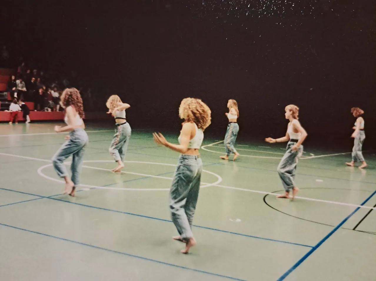 Eine Gruppe von Frauen tanzt auf einem Basketballplatz.