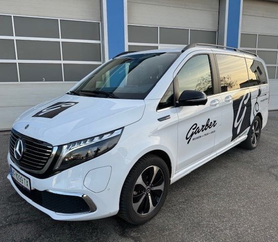 Ein weißer Mercedes-Benz V-Klasse Van mit schwarzen Akzenten und dem Wort Garber an der Seite ist vor einer Garage geparkt.