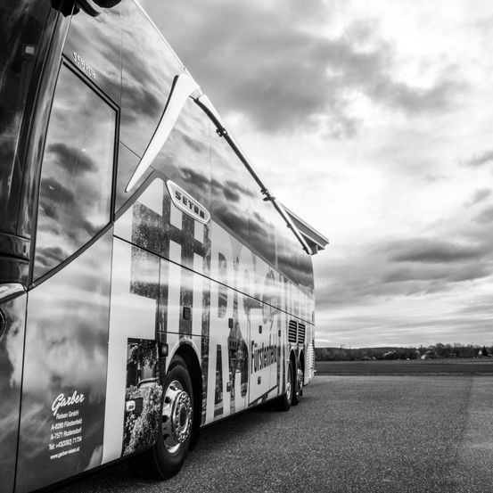 Ein schwarz-weißes Bild eines Busses mit dem Wort 'SETRA' an der Seite. Der Bus ist auf einer Straße geparkt, mit einem bewölkten Himmel im Hintergrund.