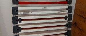 Ein Stapel zusammenklappbarer Betten mit roten und weißen Streifen ist ausgestellt. Ein weißes Schild mit schwarzem Text zeigt einen Preis von 6,29 an.