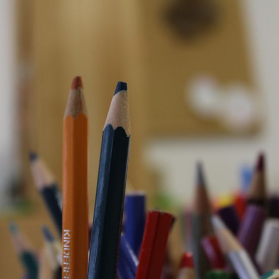 Ein Nahaufnahme von verschiedenen farbigen Stiften, darunter orange und blau, mit einem verschwommenen Hintergrund.