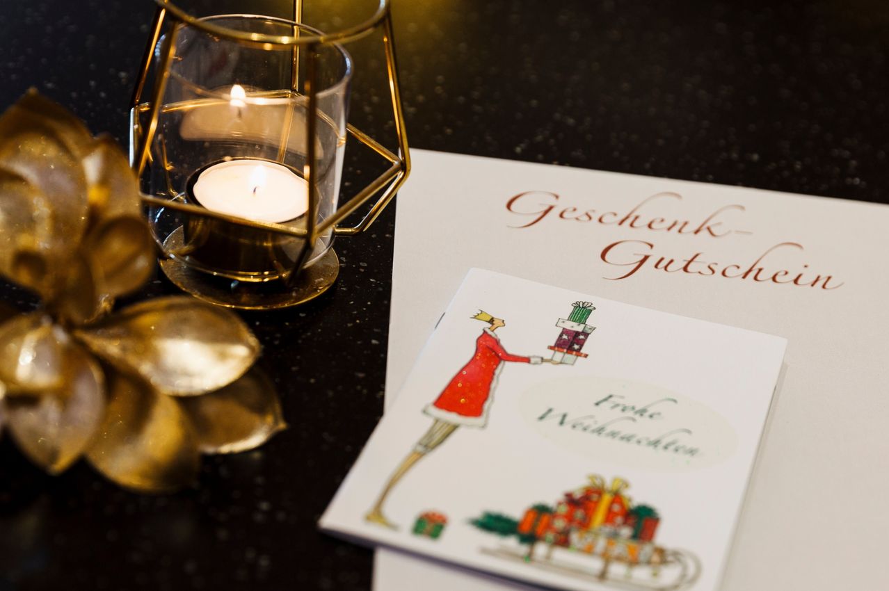 Eine Weihnachtskarte mit einer festlichen Szene, einer Kerze in einer goldenen Laterne und einem Tisch, geschmückt mit festlichen Gegenständen.