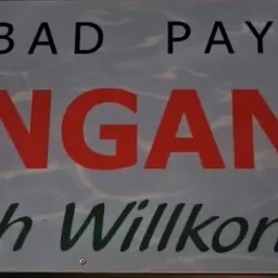 Ein Schild auf Deutsch mit dem Text 'Reibad Payerb Eingang Herzlich Willkommen' und einem Wasserhintergrund.
