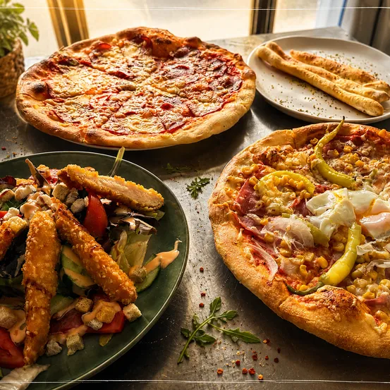 Drei Teller mit Essen auf einem Tisch: eine Pizza mit Peperoni, eine Pizza mit Mais und Eiern und ein Salat mit Hähnchen und Gemüse.