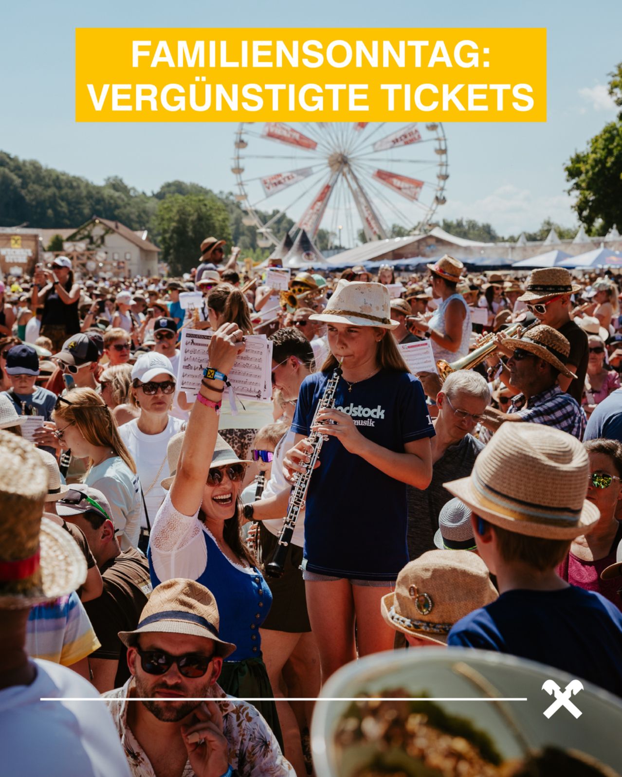 Eine Menschenmenge bei einem Musikfestival mit einem Riesenrad im Hintergrund. Eine Frau spielt Klarinette, während andere zuschauen. Viele tragen Hüte und Sonnenbrillen.