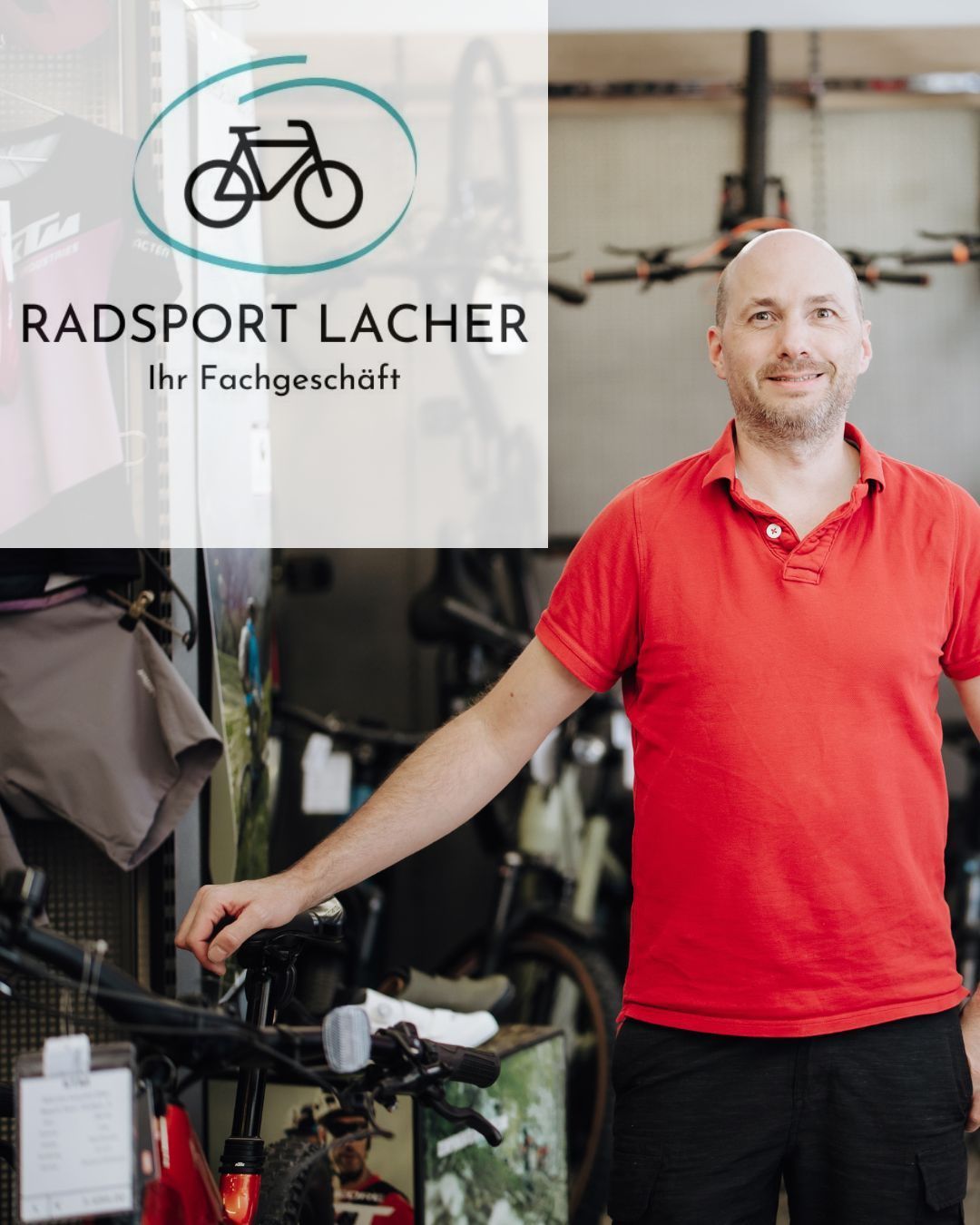 Ein Mann in einem roten Shirt steht in einem Fahrradgeschäft und lächelt. Hinter ihm steht ein weißes Schild mit der Aufschrift 'RADSPORT LACHER Ihr Fachgeschäft'. Fahrräder hängen an der Wand und an Gestellen.