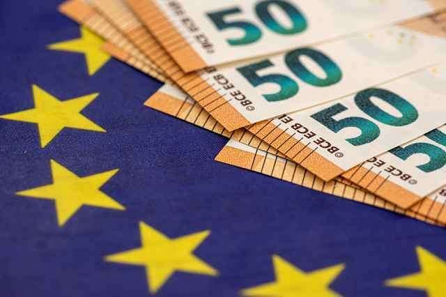 Ein Stapel von 50 Euro Scheinen auf der Flagge der Europäischen Union mit gelben Sternen.