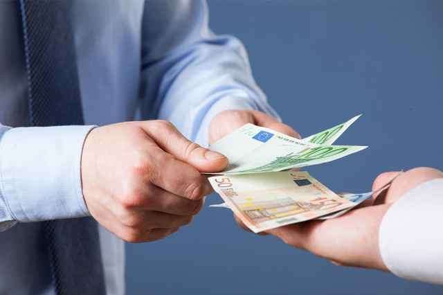 Zwei Hände tauschen einen 50-Euro-Schein aus, wobei eine Hand ihn hält und die andere ihn nimmt.