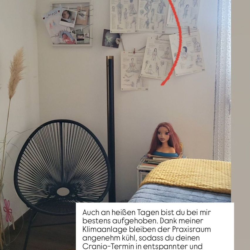 Ein Zimmer mit einem schwarzen Stuhl, einem Bett mit einer gelben Decke, einer Puppe und einer weißen Wand mit Zeichnungen und Fotos. Eine Pflanze ist auf der linken Seite.