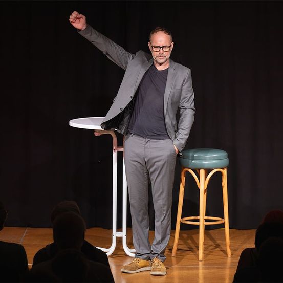 Bild enthält, Person, Solo Performance, Adult, Female, Woman, Male, Man, Coat, Furniture, Bar Stool