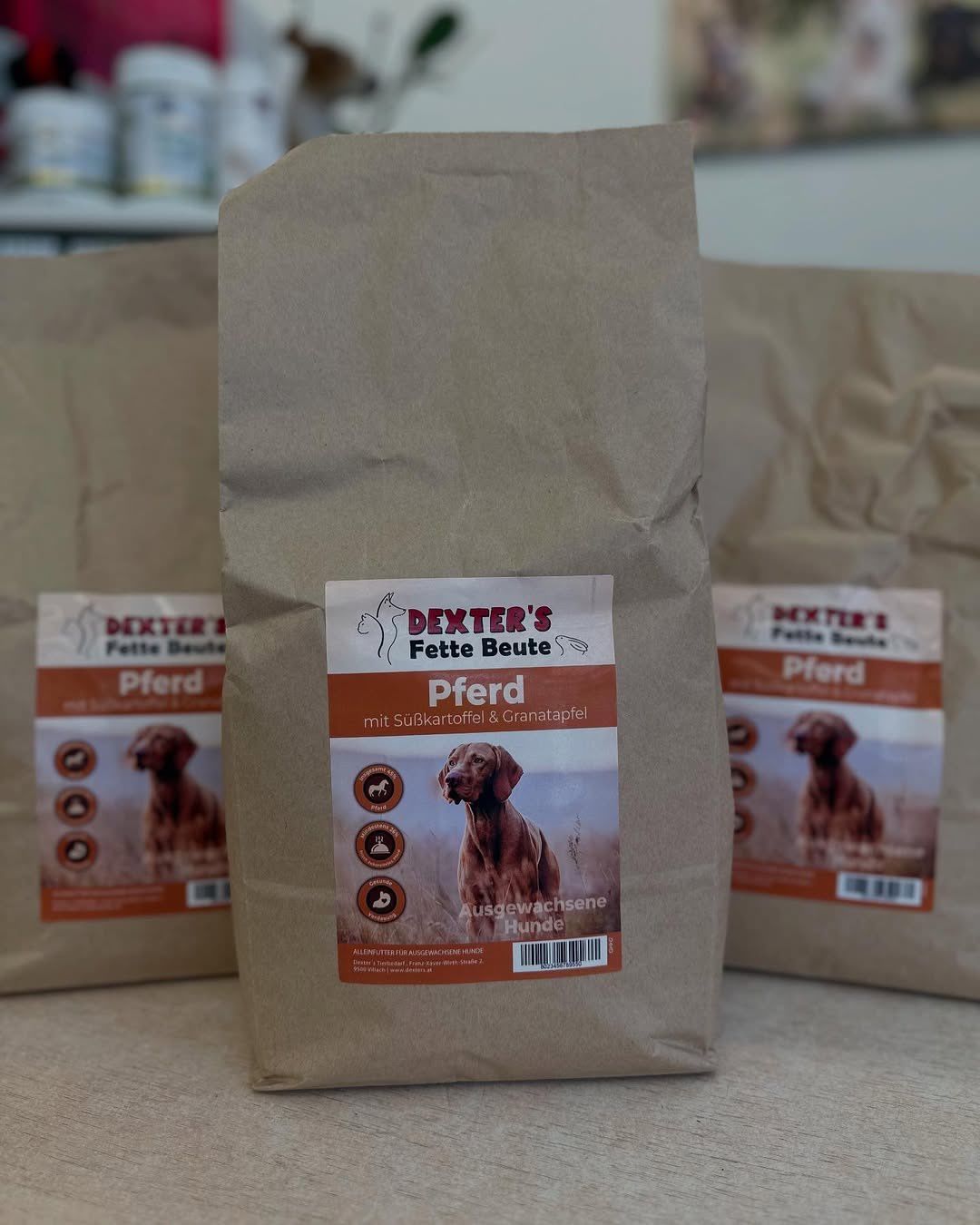 Drei braune Papiertüten mit der Aufschrift Dexter's Fett Beute Pferd. Die Vorderseite zeigt ein Bild eines braunen Hundes mit einem Etikett für wachsende Hunde mit Süßkartoffel und Grapefruit.