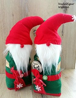 Zwei Gnome mit roten Mützen und weißen Bärten stehen auf einer Holzoberfläche, jeder hält ein kleines Geschenk. Sie tragen grüne und rote Kleidung, rote Bänder und Schneeflocken auf ihren Mützen.