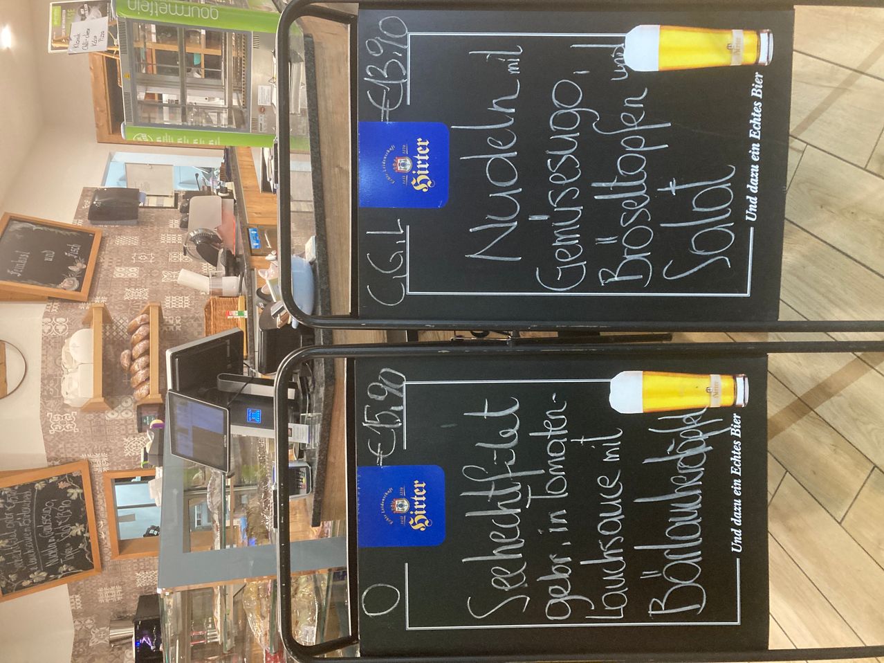 Two chalkboard menus are displayed. One says Nucleoli with Genovese sauce for 6.90 Euros, the other says Scampi fried in tomato sauce for 5.90 Euros. Both have beer labels.