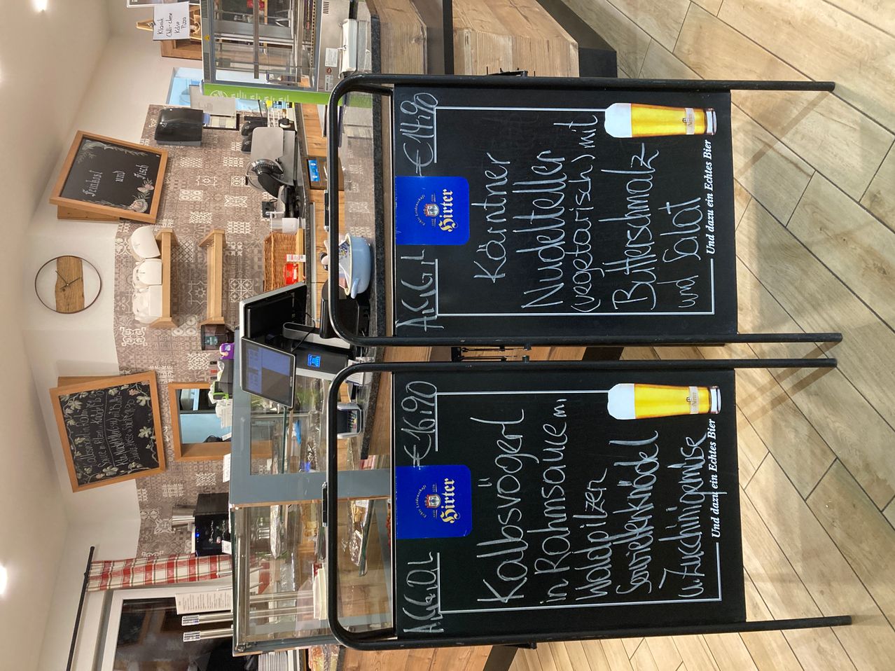 Zwei Kreidetafeln mit einem Menü, das verschiedene Getränkeoptionen anzeigt. Links ist eine Bieroption aufgeführt, zusammen mit anderen Getränken. Rechts ist eine weitere Bieroption mit ihren Zutaten aufgeführt.