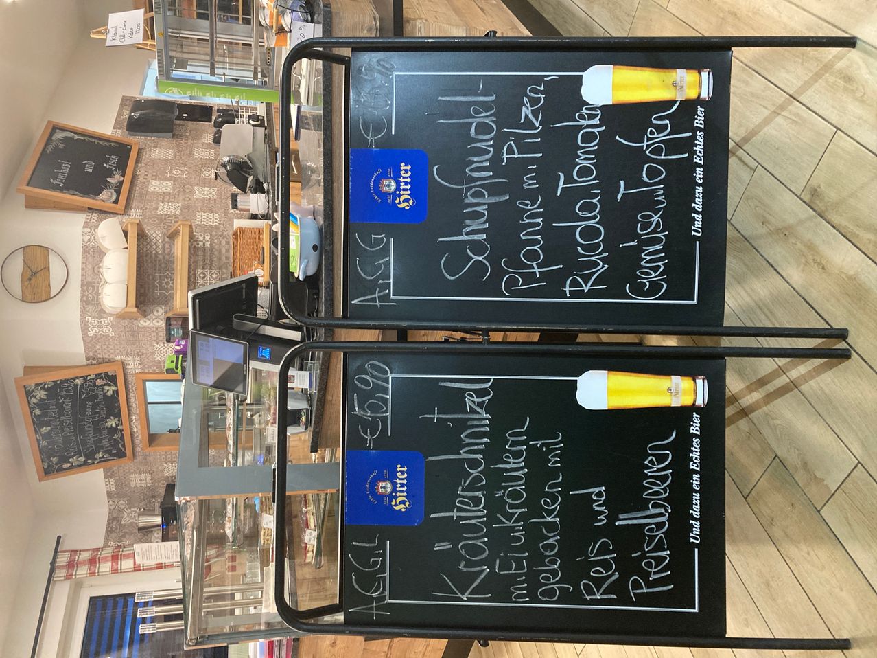 Two chalkboards with handwritten beer menu and prices in a restaurant. The top board has a price tag for 'Schulpraudel' and 'Fanne in Pilzen'. The bottom board has a price tag for 'Kauftschnaps' and 'Reis und Reis'.