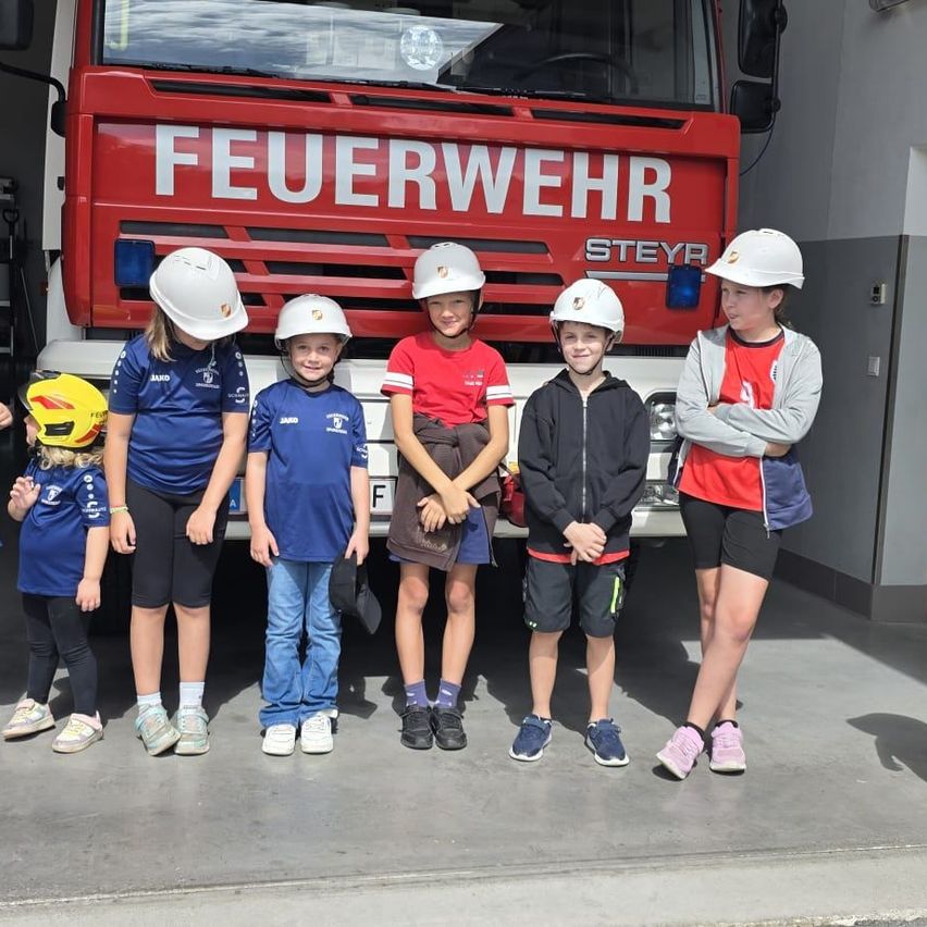 Kinder mit Helmen vor einem Feuerwehrauto der Feuerwehr Steyr