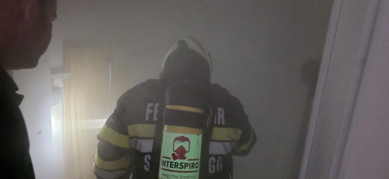 Ein Feuerwehrmann in voller Uniform mit einem Interspiro-Atemschutzgerät. Die Jacke zeigt die Buchstaben FE und GG.
