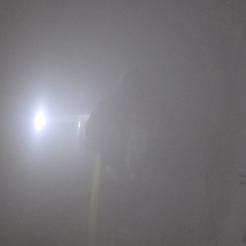 Eine Person in einem dunklen, nebligen Bereich mit einem hellen Licht, das von links beleuchtet.